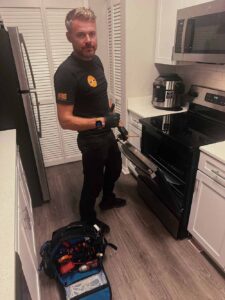 Fix It All Masters technician beside a kitchen oven